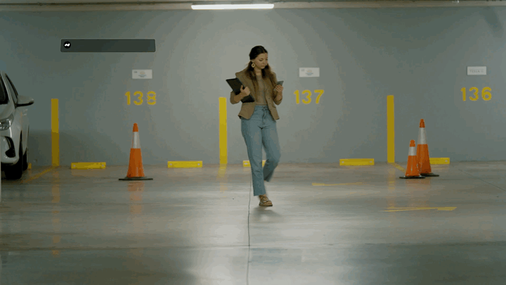 Una chica camina por un estacionamiento mientras aparecen en pantalla las notificaciones y mensajes de texto de su celular
