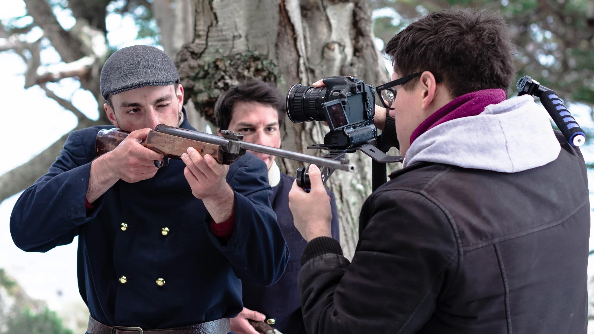 Kevin filma con cámara al hombro a un actor con uniforme de época apuntando un rifle