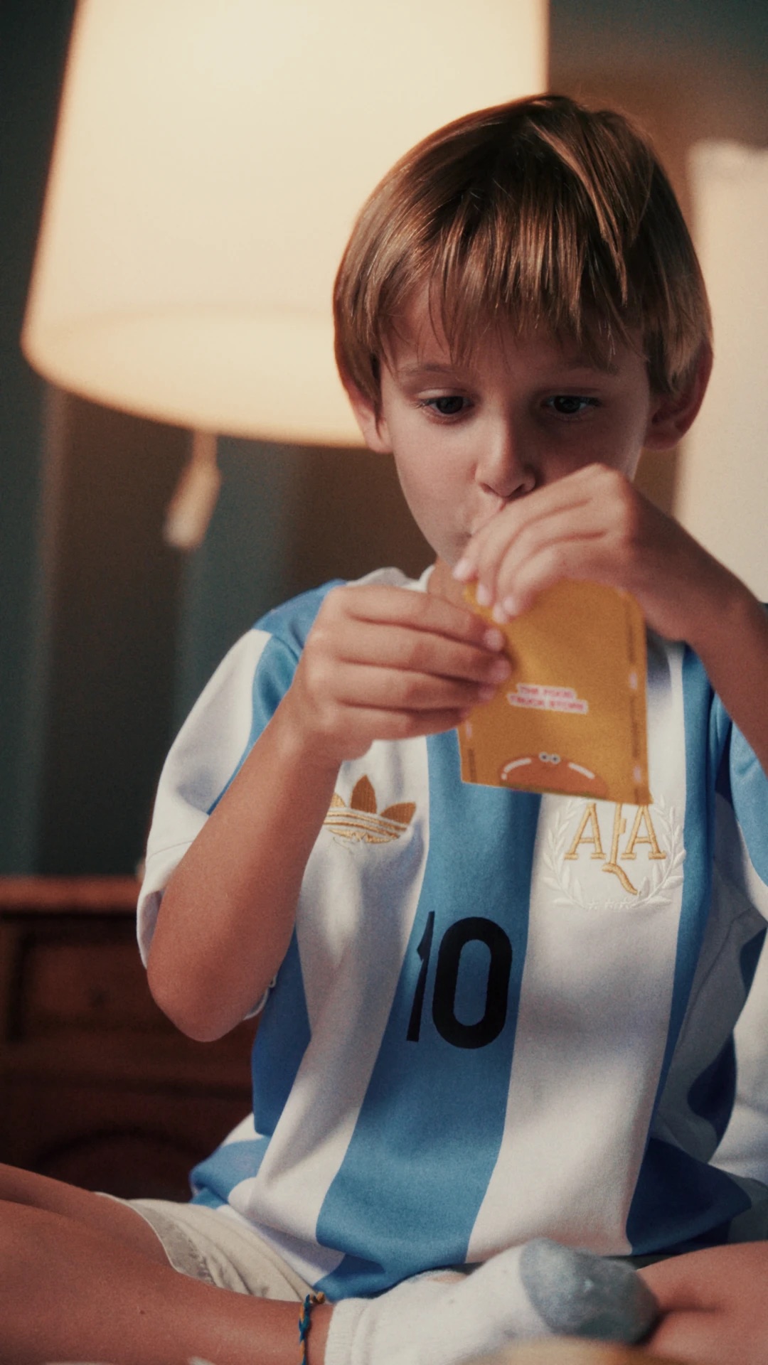 Campaña Álbum TFTS Mundial: nene con la camiseta argentina abriendo un sobre, después del color grading