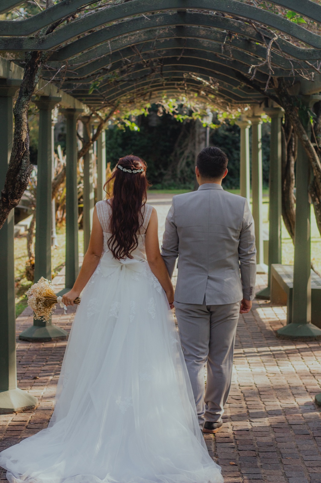 Agus and Giuliano walk hand in hand under a pergola