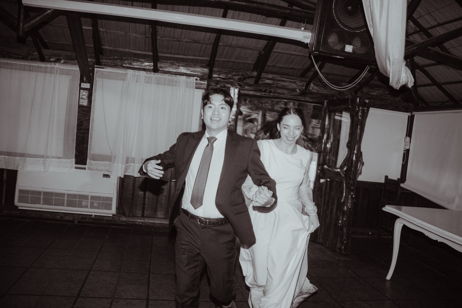 Chi Hun and Ludmila run hand in hand into the reception, in black and white
