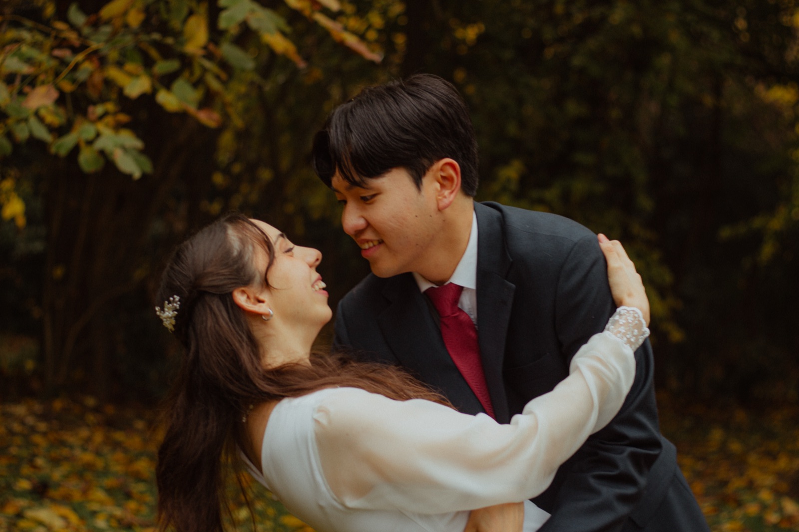 Chi Hun and Ludmila embracing among autumn trees