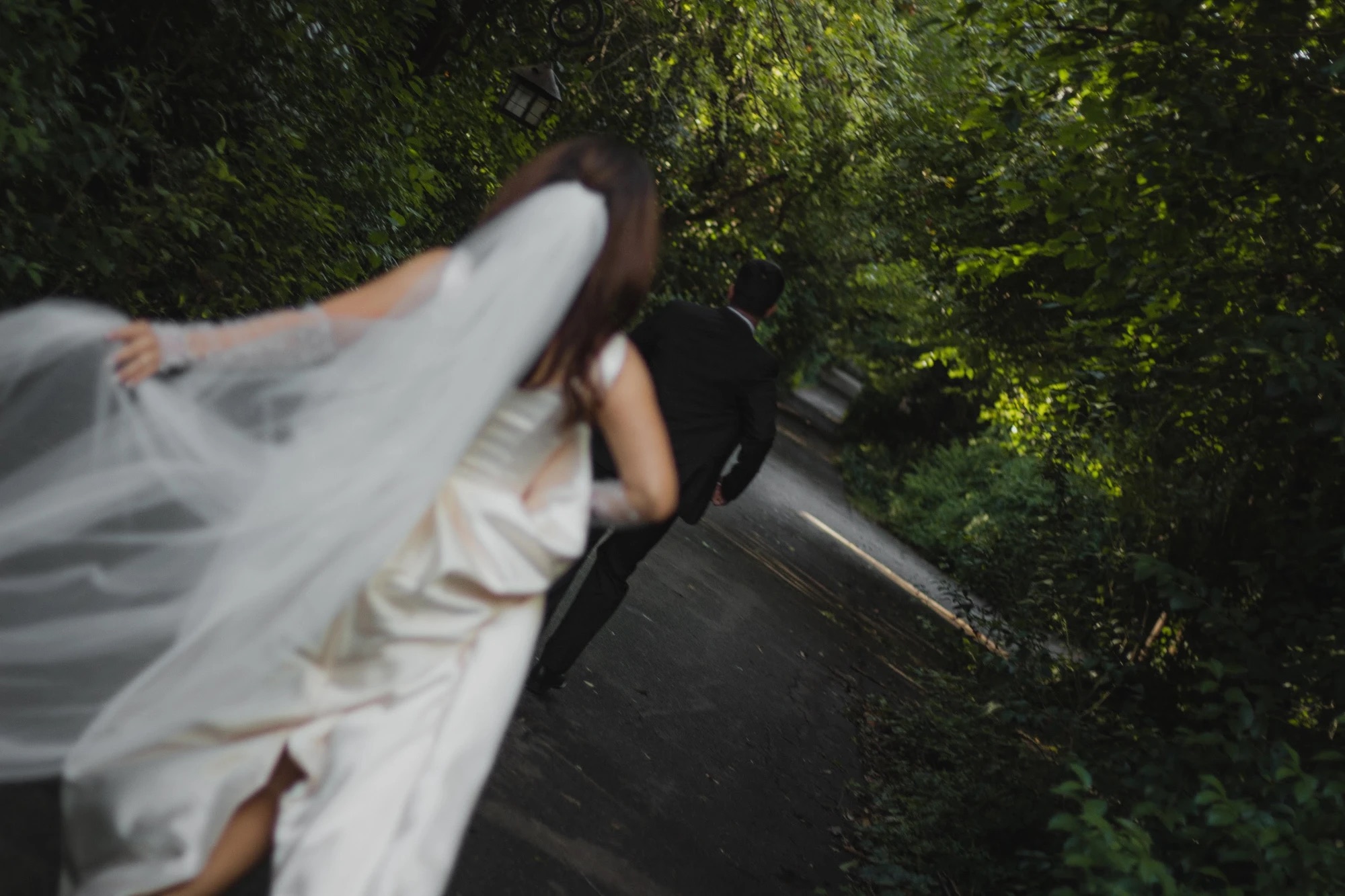Mica runs after Paco along a tree-lined path, her veil in the wind