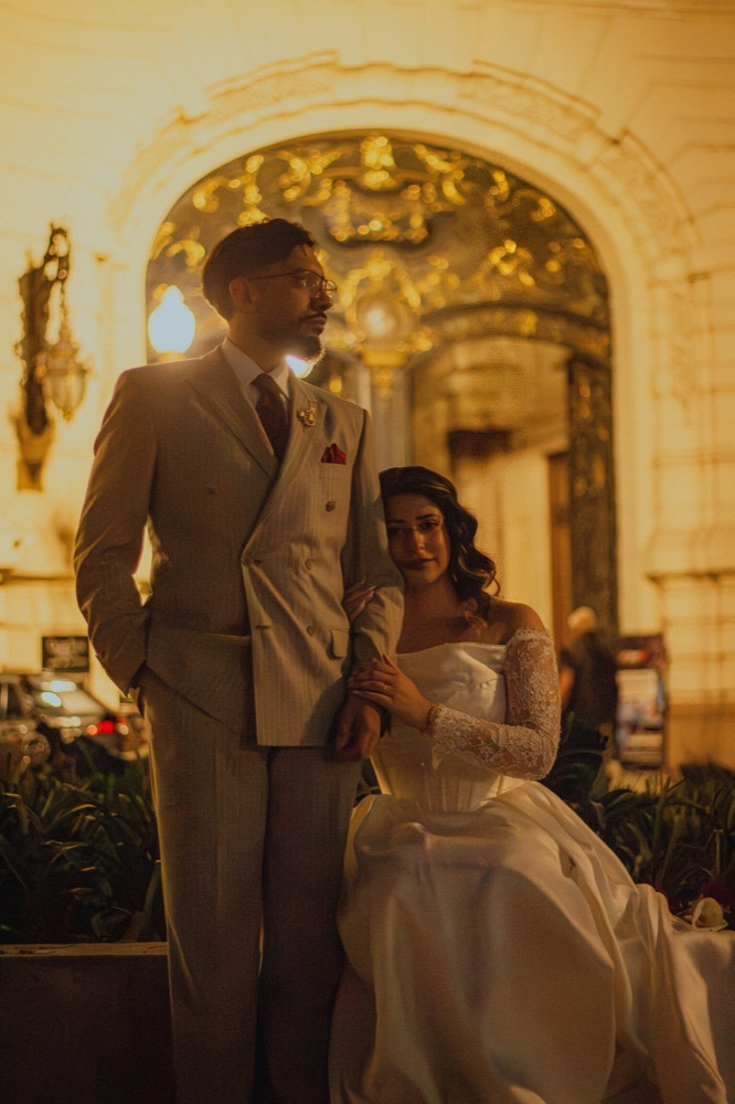 Luanne y Ramiro frente a la entrada de un palacio iluminado